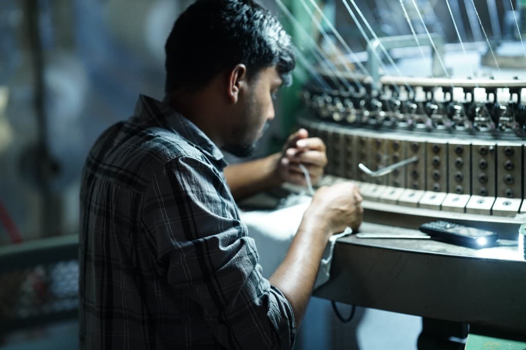 Technician adjusting yarns on an industrial circular knitting machine